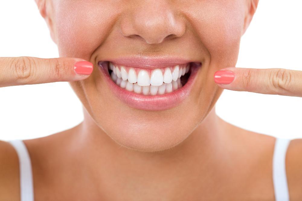 Patient pointing at her smile after professional teeth whitening in Tampa FL