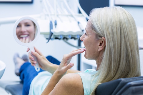 Patient checking improved smile in mirror after porcelain veneers treatment in Carrollwood Village, FL
