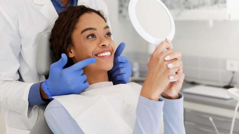 A woman smiling and checking her teeth after a Cosmetic treatment in Tampa, FL