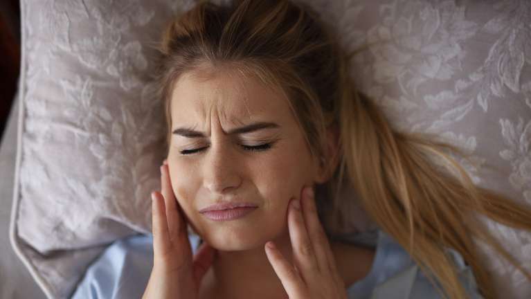 Lady holding her jaw due to migraines in Tampa, FL