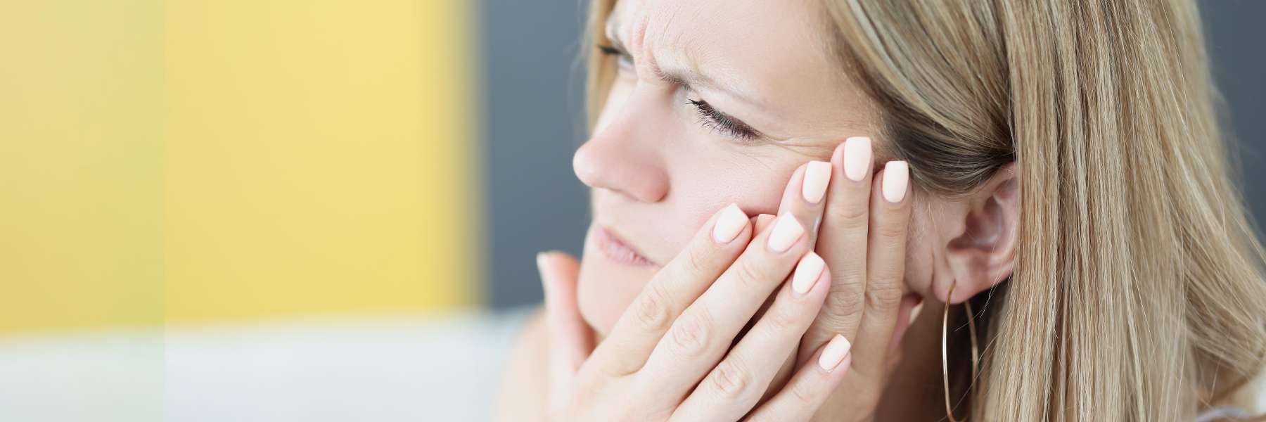 A woman holding her cheek due to a toothache in Tampa, FL